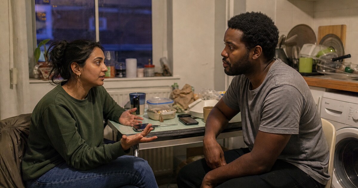 A South Asian woman in her early thirties wearing a faded green jumper and jeans and a Black man in his early thirties wearing a plain grey…
